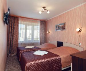 a hotel room with two beds and a television at Olginskaya Hotel in Pskov