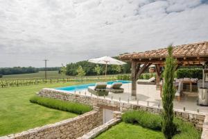 un patio trasero con piscina y cenador en Luxury French Stone Country House, en Pellegrue