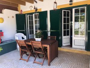 una mesa de madera y sillas en un patio en Casa da Oliveira, en Vila Nova de Milfontes
