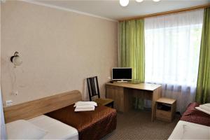 a hotel room with a bed and a desk with a computer at Olginskaya Hotel in Pskov
