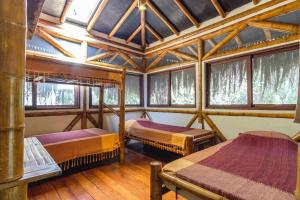 a room with three beds in a room with windows at Universo Pol Bamboo Hostel in Morro de São Paulo