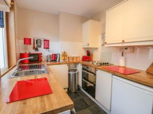 cocina con armarios blancos y encimera roja en Crinan Canal Cottage No8, en Lochgilphead