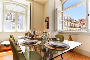 a dining room with a table and chairs and two windows at Downtown Santa Justa by Homing in Lisbon