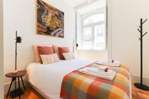 a bedroom with a white bed with a colorful blanket at Downtown Santa Justa by Homing in Lisbon