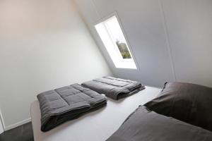 2 bedden in een witte kamer met een raam bij Ut Endt Vlieland in Oost-Vlieland