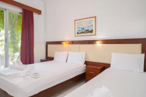 a hotel room with two beds and a window at Chrissafis Hotel in Panagia