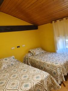 Duas camas num quarto com paredes amarelas e uma janela em Hostal Rural Oricáin em Oricáin