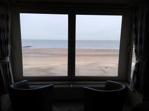 a window with two chairs looking out at the beach at toplocatie Middelkerke frontal sea view in Middelkerke