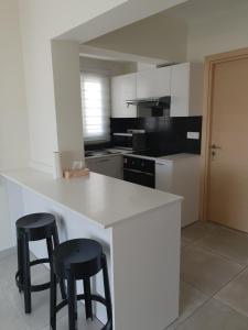 eine Küche mit einer weißen Theke und zwei schwarzen Hockern in der Unterkunft Egkomi Luxury Suites in Nikosia