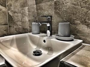 Un lavabo con dos tazas encima. en Luxury 2 Bed 2 Bath Apartment 18 mins from Central London - SLEEPS 6, en Watford