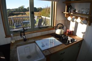 a kitchen with a sink and a stove and a window at Rose Shepherds Hut in Badlesmere