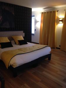 a bedroom with a large bed with yellow curtains at Le Continental in Condom