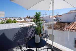 una mesa y sillas en un balcón con sombrilla en VI MAR - GUEST HOUSE en Lagos