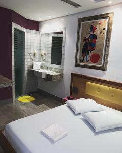 1 dormitorio con 1 cama y baño con lavamanos en Auhe Motel (Adults only), en Betim