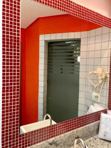 a mirror in a bathroom with red and white tiles at Auhe Motel (Adults only) in Betim