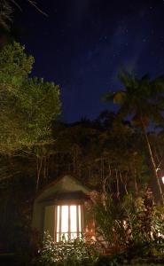 uma pequena casa com uma luz de lado à noite em Chalé Gaia - Itatiaia em Itatiaia