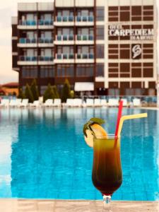 a drink sitting on a table in front of a pool at Carpediem Diamond Hotel in Karasu