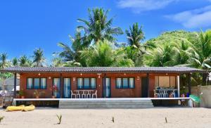 a house on the beach with palm trees in the background at Fisherman's Cottage El Nido in El Nido +61 photos