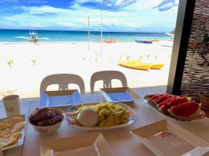 una mesa con platos de comida en una playa en Fisherman's Cottage El Nido en El Nido