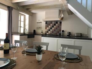 cocina con mesa de madera y copas de vino en La Folie des Remparts, en Carcassonne