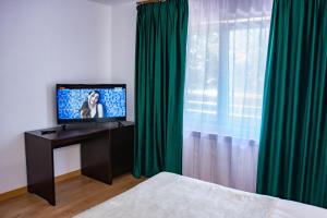 a bedroom with a television and green curtains at Hotel THR Center in Curtea de Argeş