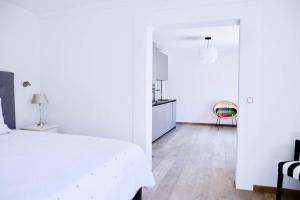 a white bedroom with a white bed and a kitchen at GLYCINES COUNTRY GUESTHOUSE in Goupillières