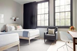 a bedroom with two beds and a chair and a desk at Quirk Hotel Richmond in Richmond