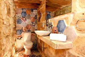 Baño de piedra con lavabo y aseo en The Lodge en Cospicua
