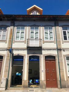 ein großes Backsteingebäude mit roten Türen und einem Balkon in der Unterkunft Carmo House in Braga