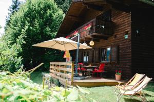 eine Holzhütte mit einem Tisch, Stühlen und einem Sonnenschirm in der Unterkunft Knusperhäuschen in Sattendorf