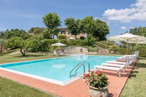 a pool with chairs and umbrellas in front of a house at Agriturismo Il Poggiarello in Siena