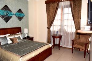 a bedroom with a bed and a chair and a window at Alejandrina Hotel in Cuenca