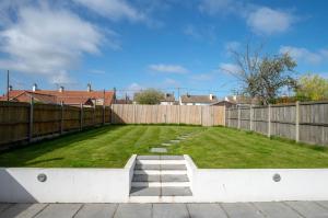 a large backyard with a fence and grass at Avocet House in Wells next the Sea