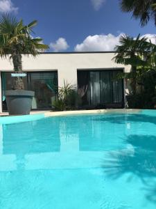 une grande piscine bleue en face d'une maison dans l'établissement La Palmeraie, à Vannes