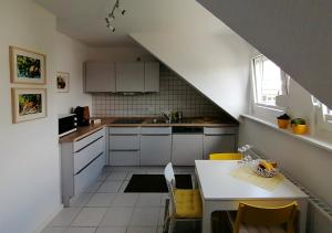 a kitchen with white cabinets and a table with yellow chairs at Ferienwohnung Grete in Trier
