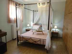 a bedroom with a four poster bed with curtains at Villa Elpida in Svoronata