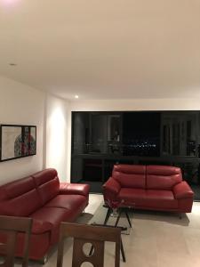 a living room with two red leather couches and a television at APARTAMENTO CON LA MEJOR VISTA DE SAN SALVADOR in San Salvador