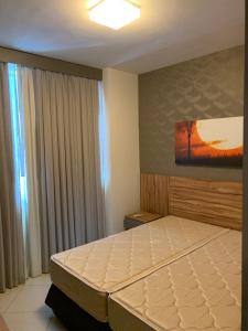 a bedroom with a large bed with a painting on the wall at Barretos Park Hotel - Condo Hotel in Barretos