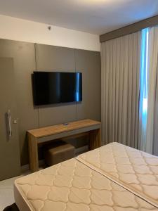 a bedroom with a bed and a flat screen tv at Barretos Park Hotel - Condo Hotel in Barretos