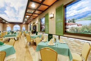 a restaurant with green tables and chairs and a large window at Dworek Eureka in Czechowice-Dziedzice