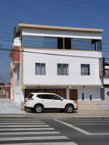 un coche blanco estacionado frente a un edificio blanco en Hostal El Salitre, en Antofagasta