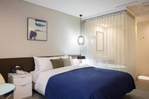 a bedroom with a blue and white bed and a window at Hotel Mate Bundang in Seongnam