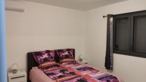 a bedroom with a bed with a purple comforter at Le Shanti - la paix in Ravine des Cafres-les Bas