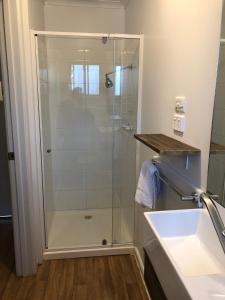 a shower with a glass door next to a sink at Bendigo Bush Cabins in Bendigo
