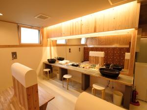a kitchen with two sinks and a counter with stools at Matsuyama New Grand Hotel in Matsuyama