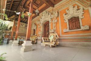 een lobby met stoelen en een standbeeld in een gebouw bij Aurora House in Ubud