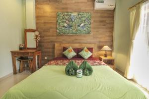 a bedroom with a large bed with a green blanket at Aurora House in Ubud