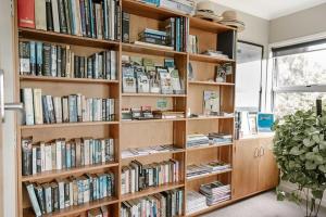 una mensola piena di libri in una stanza di The Nunnery a Te Aroha