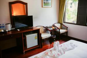 a room with a bed and a television and a desk at E-Outfitting Vang Thong Hotel in Luang Prabang