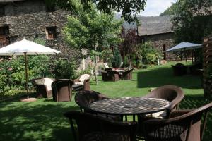 un patio con mesa, sillas y sombrilla en Hotel Vall Ferrera, en Àreu